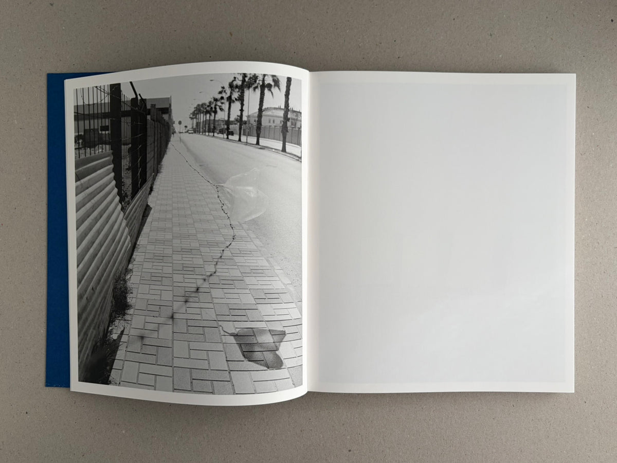Open book spread from Sub Sole by Massao Mascaro, showing a black-and-white street photograph on the left page and a blank white right page.