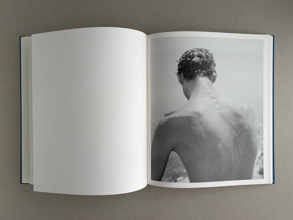 Open spread of Sub Sole – Massao Mascaro, showing a blank left page and a black-and-white photograph of a wet person seen from behind on the right page.