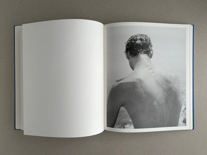 Open spread of Sub Sole – Massao Mascaro, showing a blank left page and a black-and-white photograph of a wet person seen from behind on the right page.