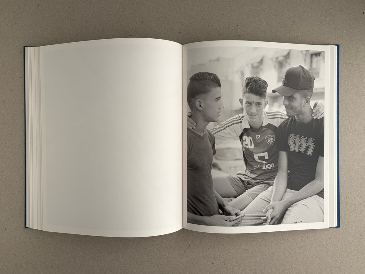 Open spread of Sub Sole by Massao Mascaro, with a black-and-white photograph of three young men on the right page and a blank left page.