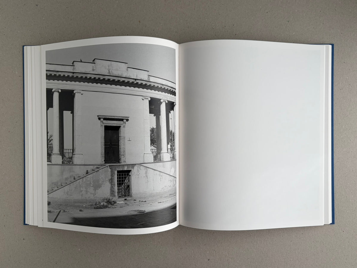Open spread of Sub Sole – Massao Mascaro, showing a black-and-white photograph of a curved neoclassical building on the left page and a blank white page on the right.