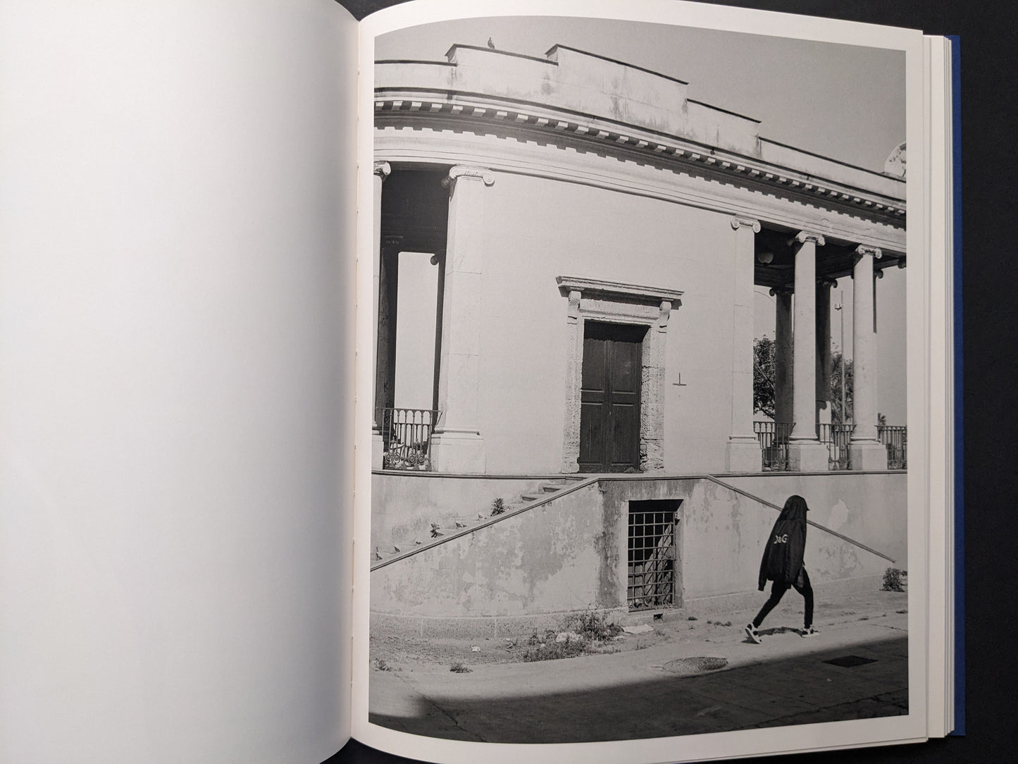 Black-and-white photograph of a rotunda-like building with a lone passerby.