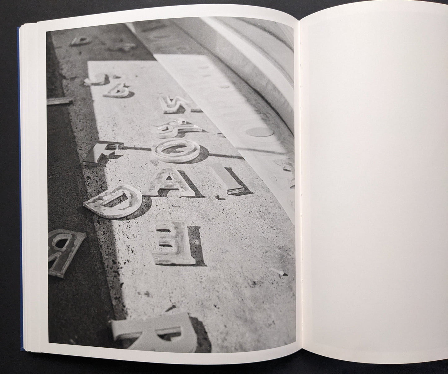 Black-and-white photograph of scattered letterforms on dusty ground.
