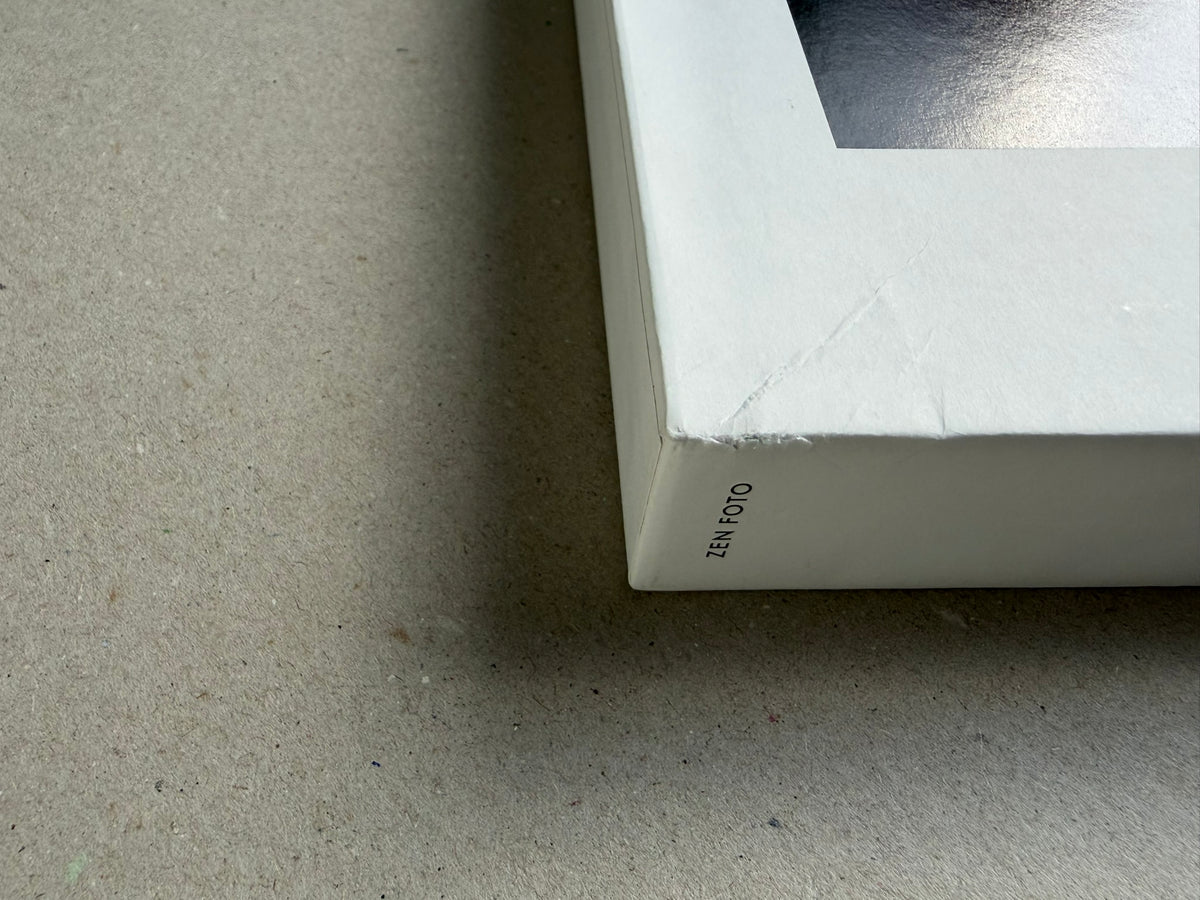 Close-up of the corner of the Surveillance – Tsutomu Yamagata book, showing the white cover, a partial image area, and the Zen Foto logo on the spine.