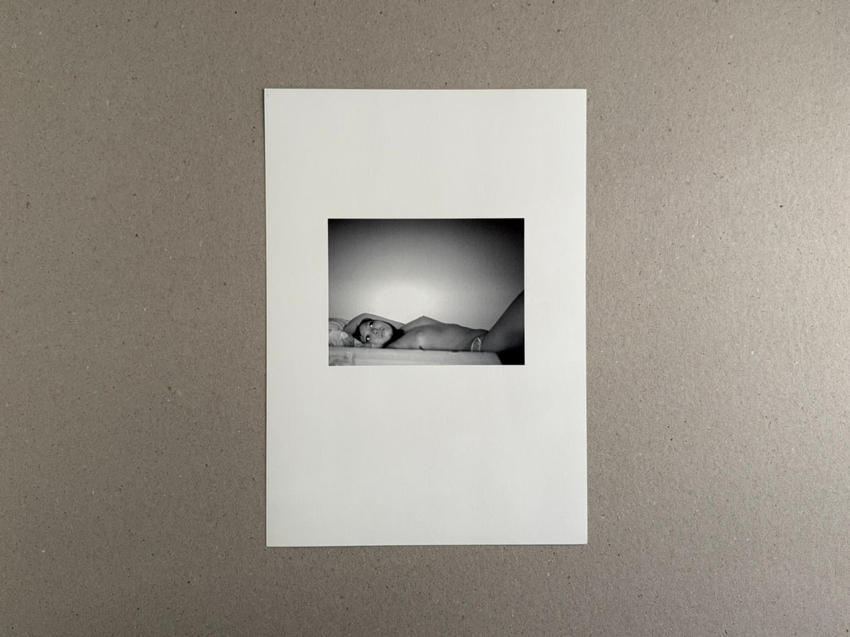 Surveillance – Tsutomu Yamagata, printed page with a small black-and-white photograph of a reclining figure centered on a white sheet.