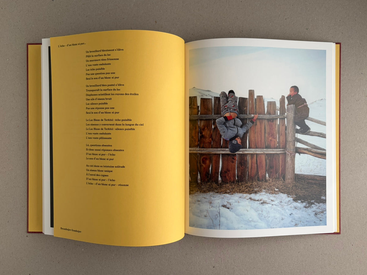 Open spread of süü – Taemin Ha, with a poem on the left page and a winter photograph of two children by a wooden fence on the right page.