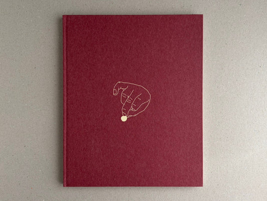Front cover of süü – Taemin Ha, a deep red clothbound book with a line drawing of a hand holding a small pale circle.