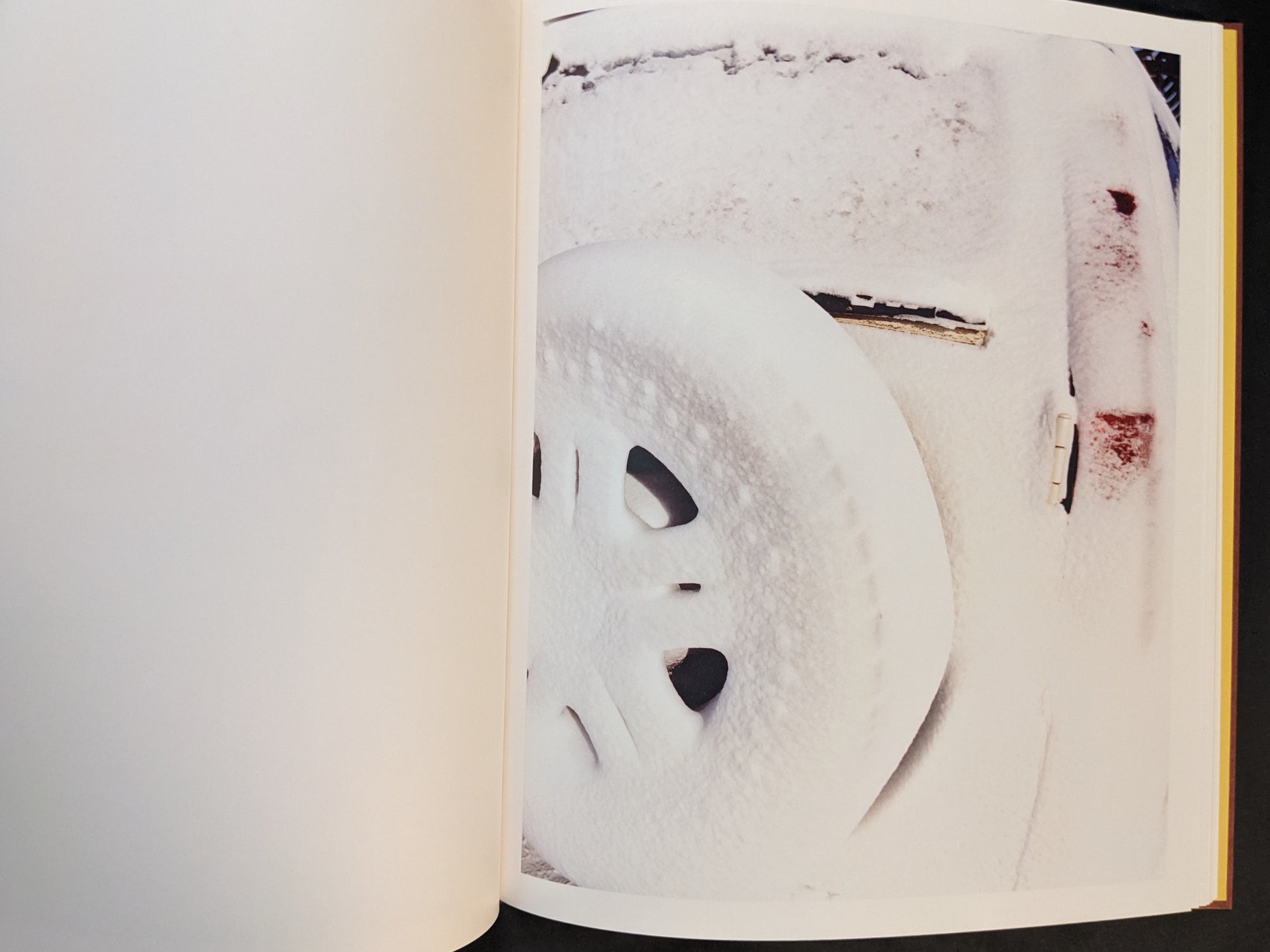 Snow-covered vehicle surface with two dark openings resembling eyes.