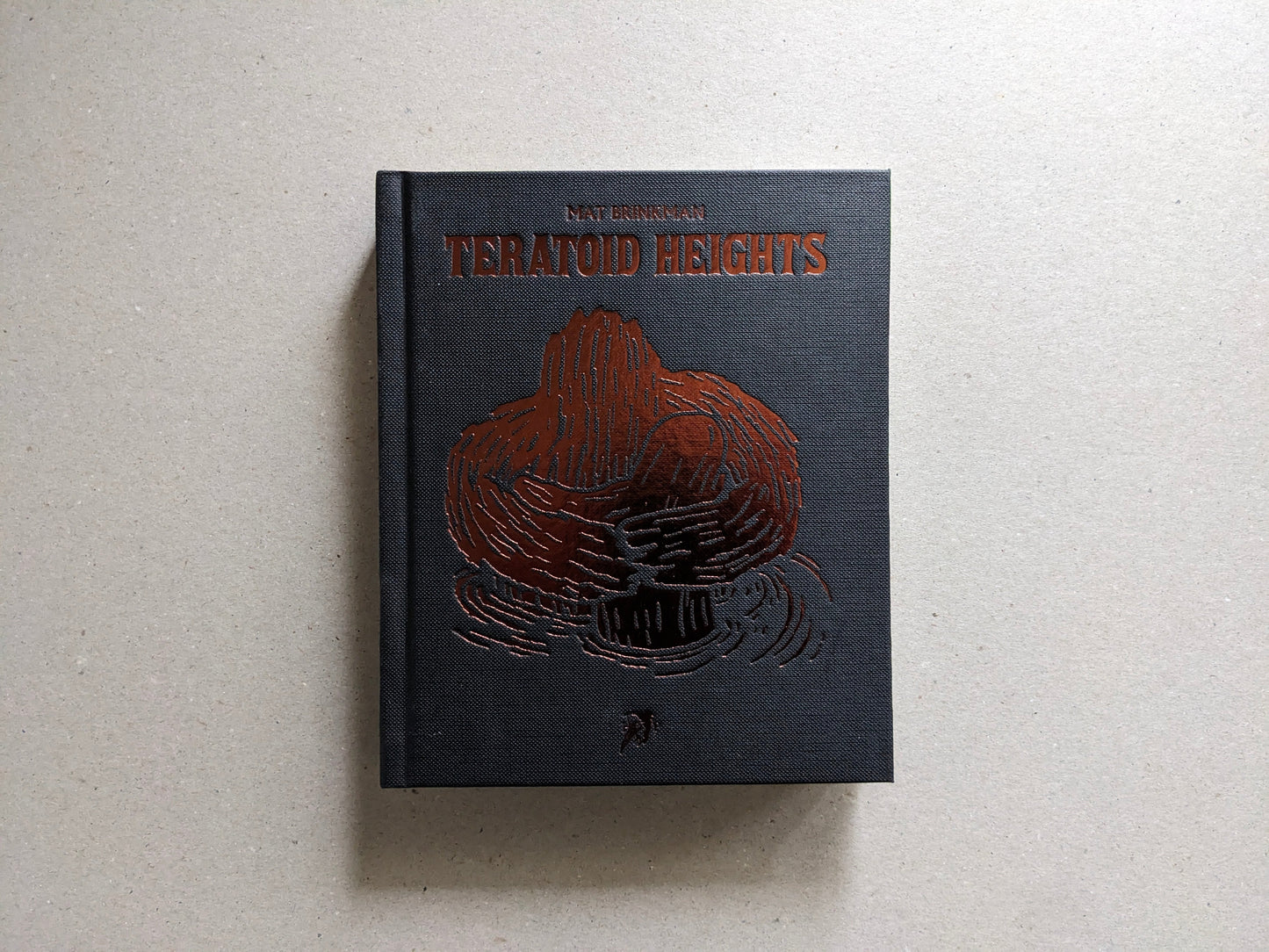 Front cover of Teratoid Heights by Mat Brinkman, black canvas hardcover with bronze foil embossing