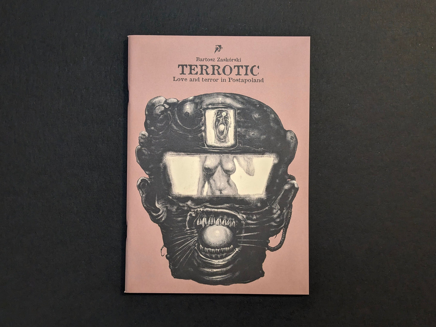 Front cover of Terrotic: Love and Terror in Postapoland by Bartosz Zaskórski, with a black biomechanical face on a muted pink background.