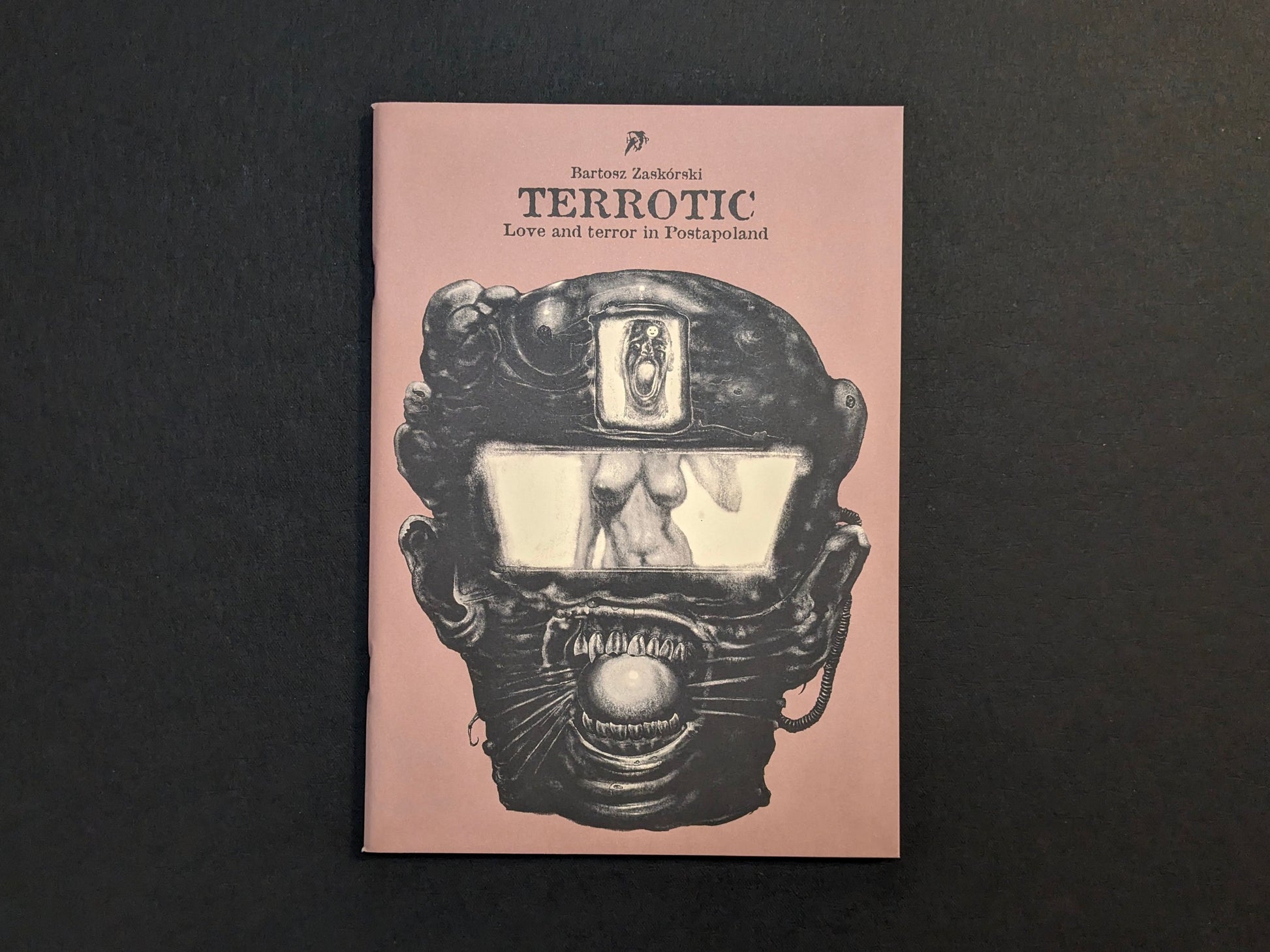 Front cover of Terrotic: Love and Terror in Postapoland by Bartosz Zaskórski, with a black biomechanical face on a muted pink background.
