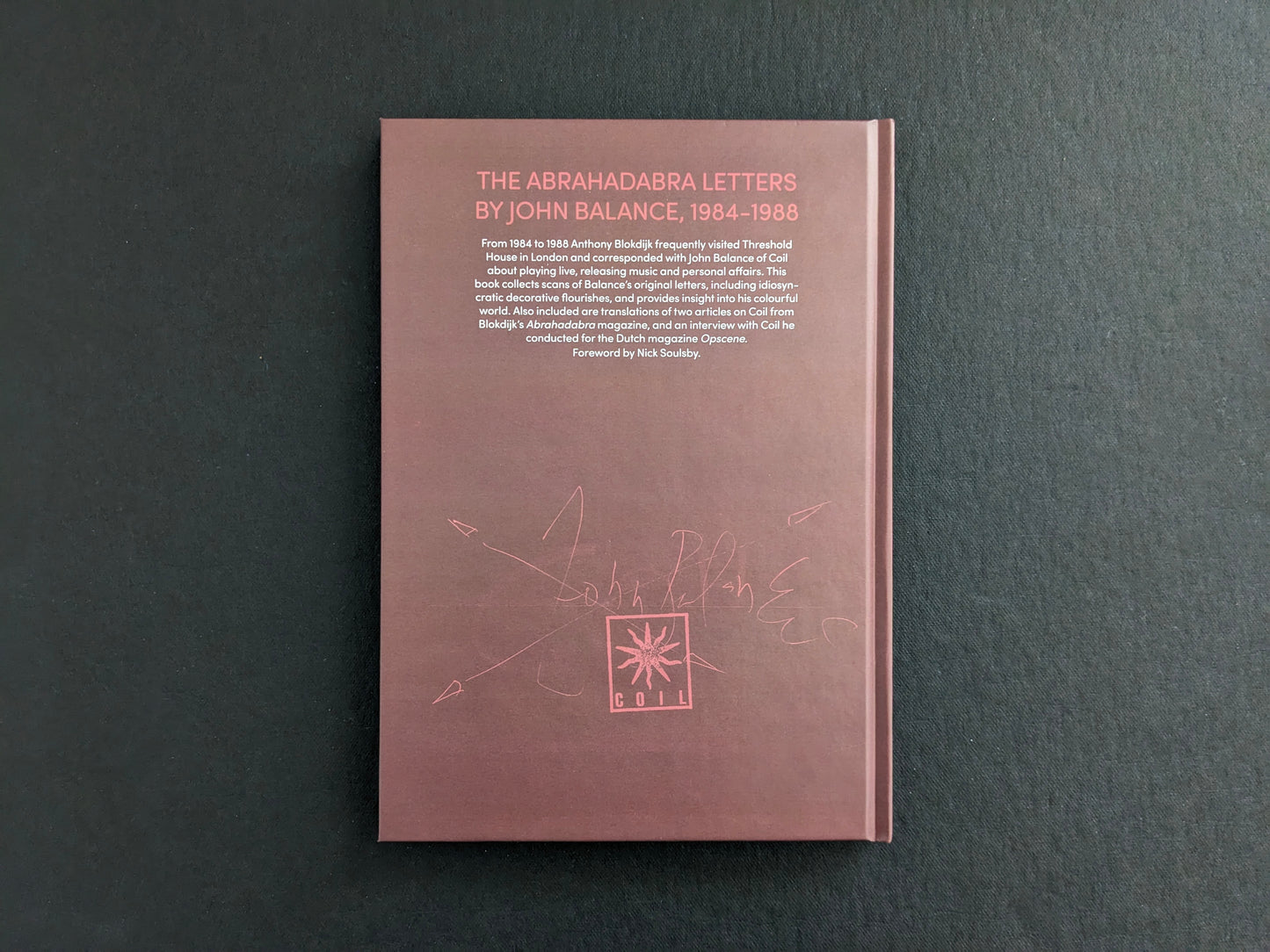 Back cover of The Abrahadabra Letters, brown clothbound boards with printed description and a Coil emblem.