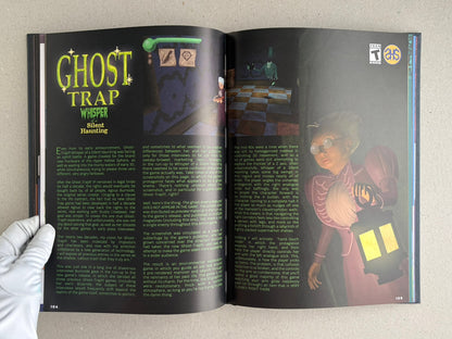 Open spread from The Bizarre World of Fake Video Games showing a two-page article on Ghost Trap: Whisper of a Silent Haunting, with game screenshots, text columns, and page numbers 104–105.