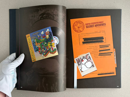 Open spread from The Bizarre World of Fake Video Games showing a dark page with a small illustrated insert on the left and an orange “Super Eyepatch Wolf Secret Archives” document on the right.