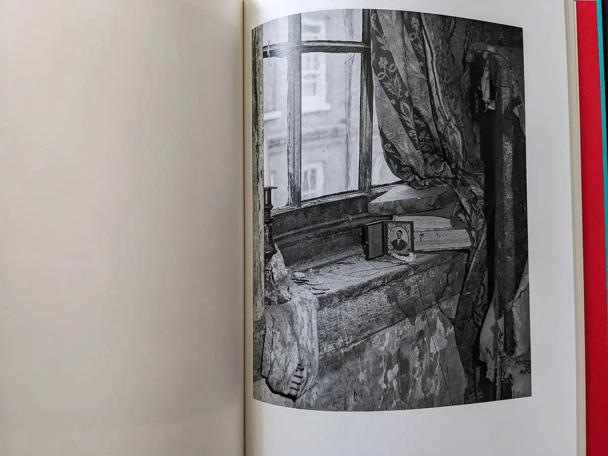 Dusty window sill with small objects and patterned curtains in an old room.