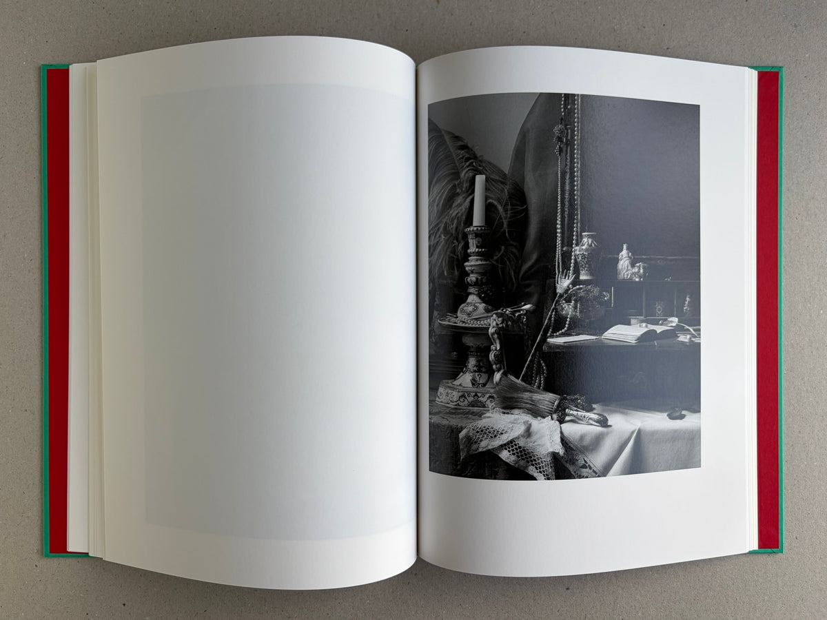 Open spread from The Essential Solitude, with a black-and-white still life of a table, candlesticks, beads, and an open book on the right page.