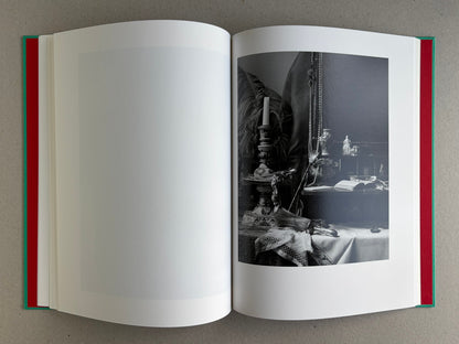 Open spread from The Essential Solitude, with a black-and-white still life of a table, candlesticks, beads, and an open book on the right page.