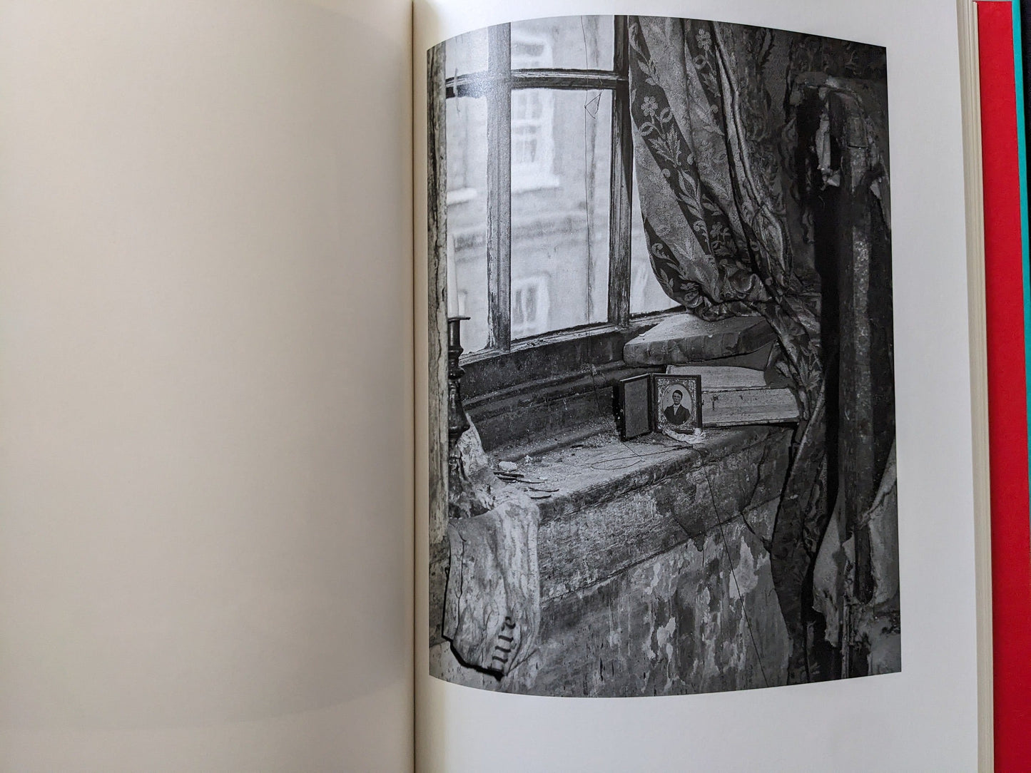 Close view of a dusty window, small objects, and patterned curtains in an old room.