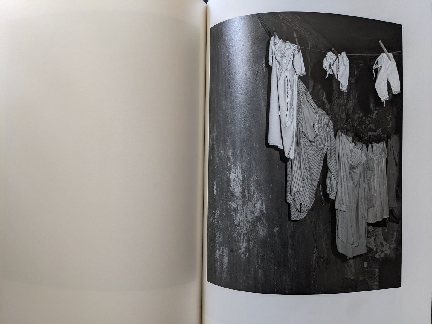Hanging white garments on a line inside a dim, aged cellar space.