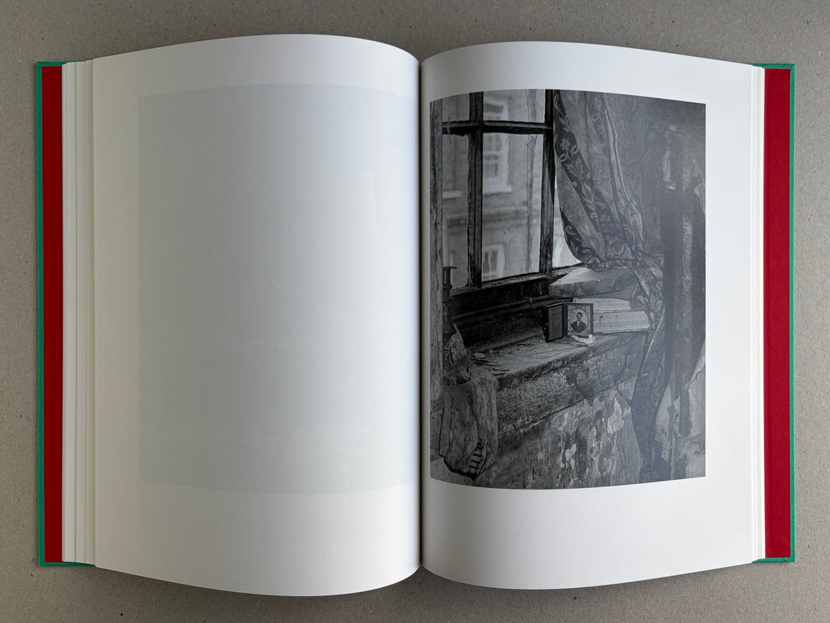Open spread from The Essential Solitude, showing a black-and-white interior scene with a window and curtain on the right page.