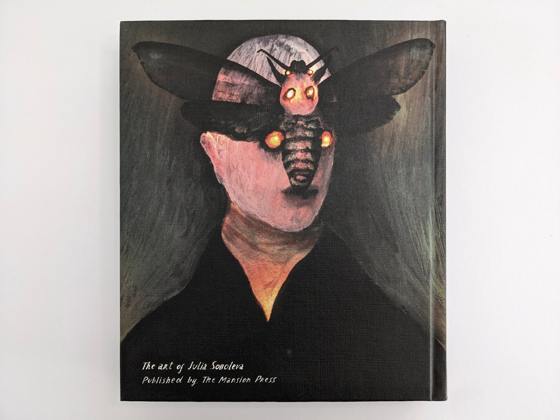 Back cover of The Fire That Drank The Shadow: The Art of Julia Soboleva, showing a moth man on a white background.
