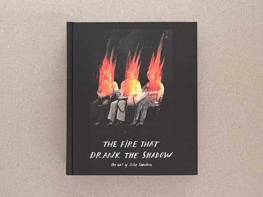 Front cover of The Fire That Drank the Shadow by Julia Soboleva, showing three seated figures with flame-like red-orange forms above them on a black background.