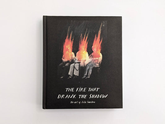 Cover of The Fire That Drank The Shadow: The Art of Julia Soboleva, showing three seated figures with flame-like heads on a white background.
