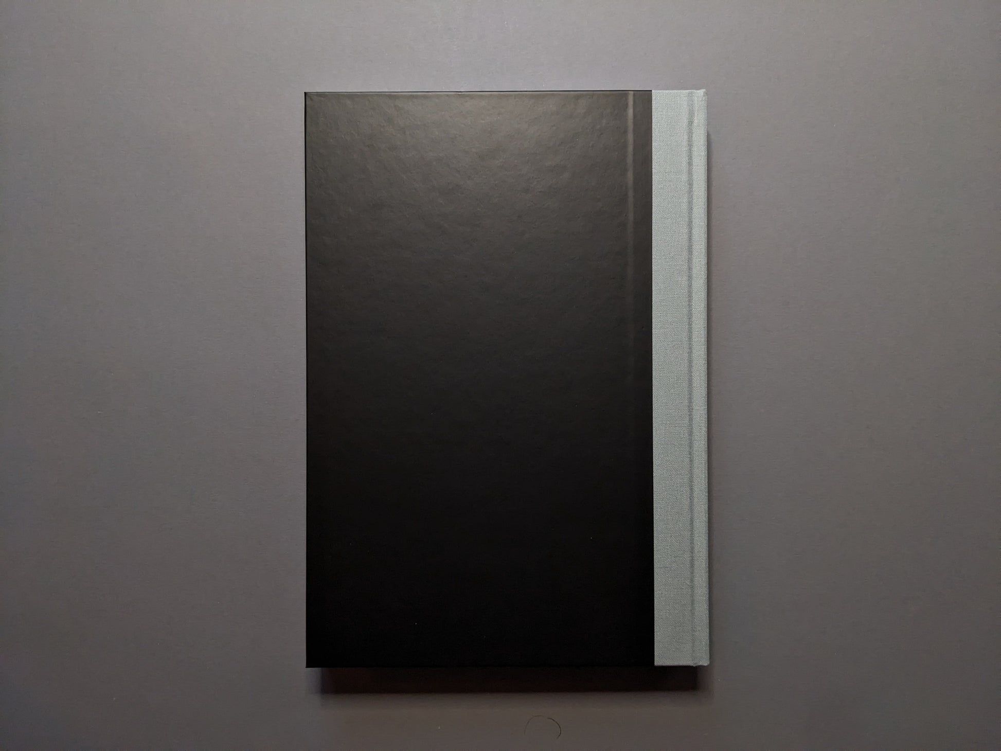 Back cover of 'The Last Slogan' – minimalist black with grey cloth spine