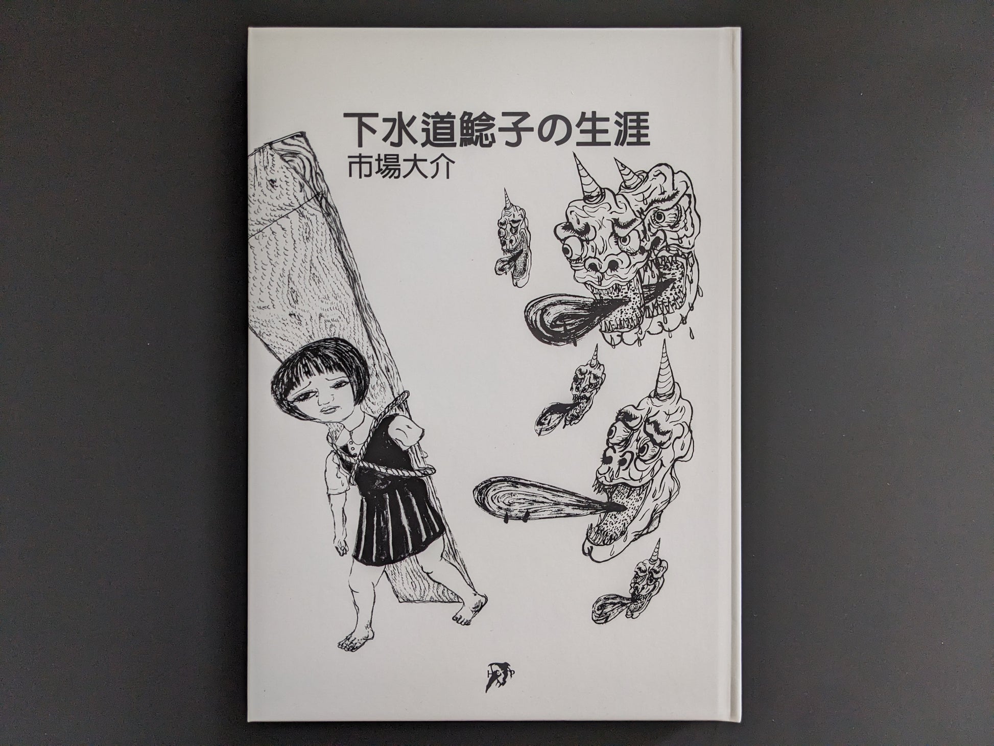 Front cover of “The Life of Namazuko” by Daisuke Ichiba, showing a girl carrying a heavy plank and grotesque floating heads in monochrome.