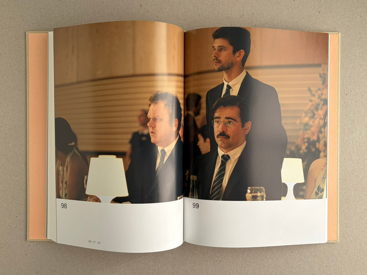 The Lobster Screenplay Book open to a two-page film still, showing men in suits seated at a formal dinner.