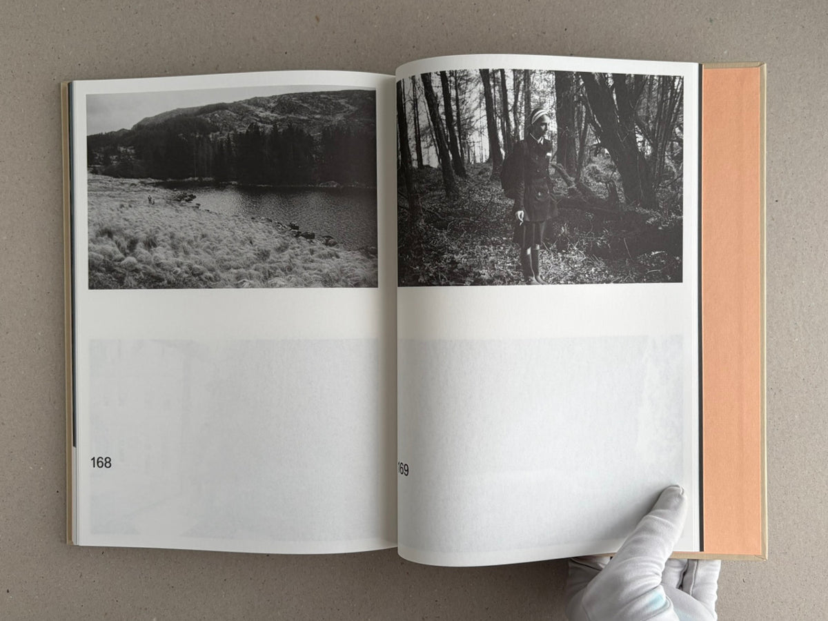 Open spread of The Lobster Screenplay Book showing black-and-white film stills on pages 168 and 169, with a gloved hand holding the book open.