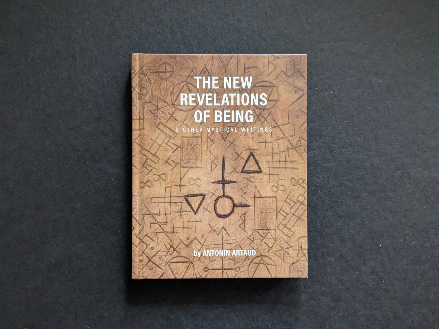 Front cover of The New Revelations of Being by Antonin Artaud, with esoteric symbols on a textured brown background.