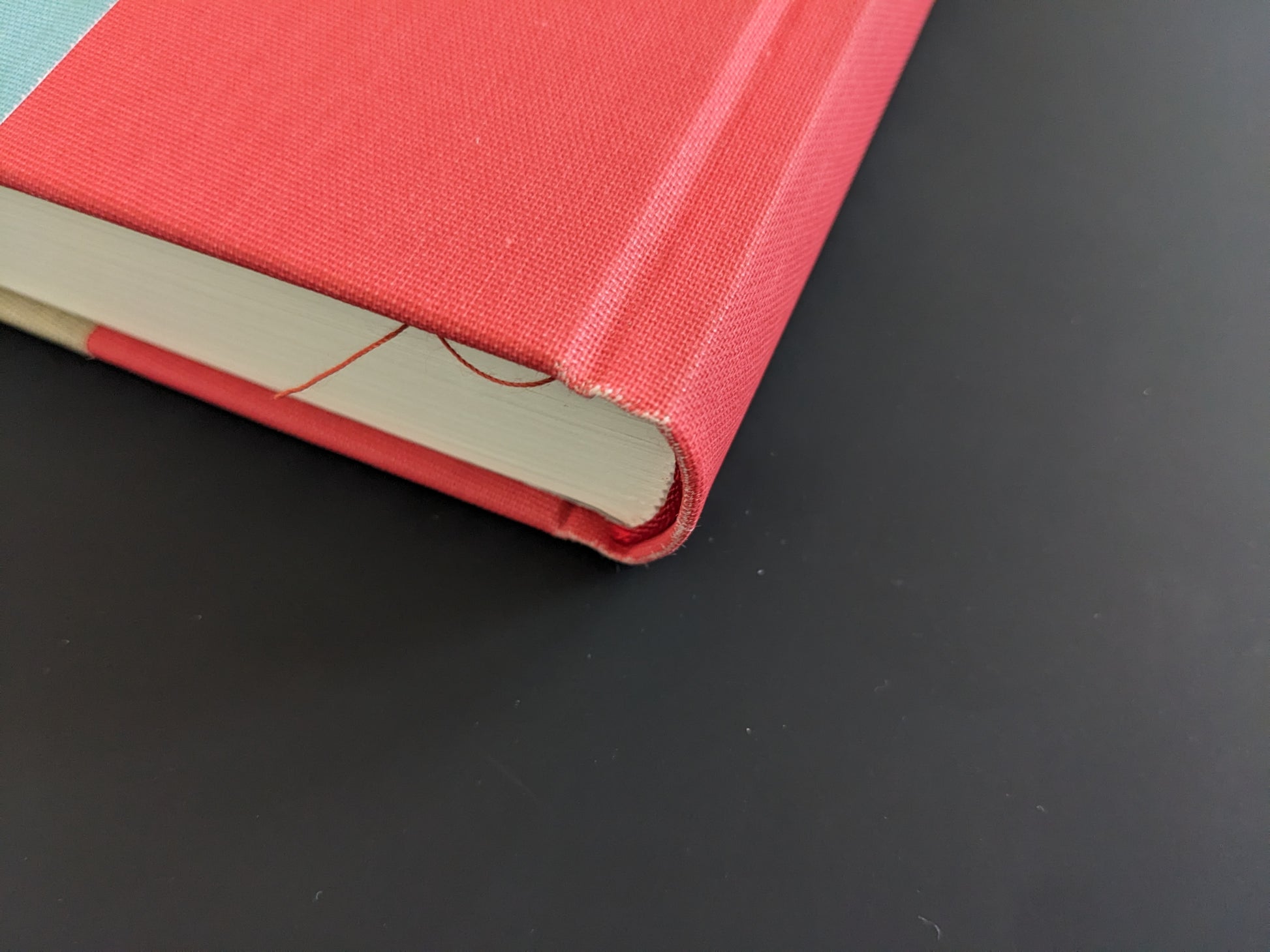 Bottom spine corner of The Pillar by Stephen Gill, red cloth cover showing frayed edges