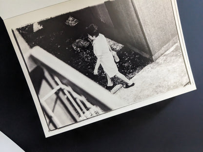 Black-and-white photo of a woman in a white dress walking in an urban setting