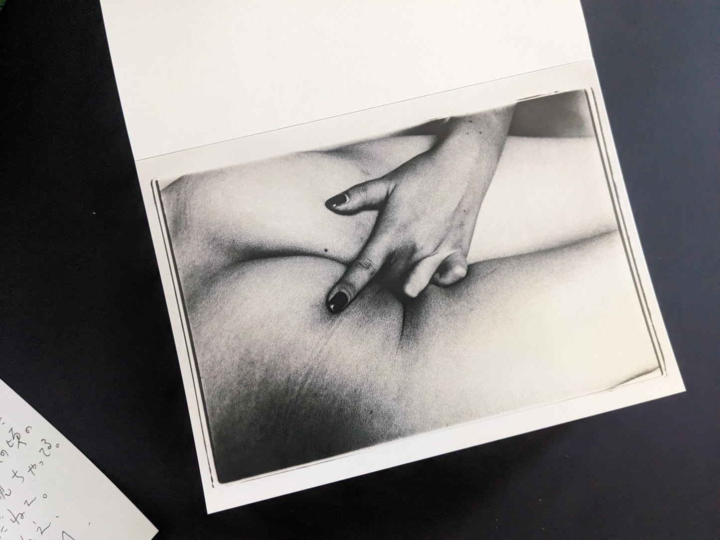 Close-up black-and-white print of a hand on a nude body