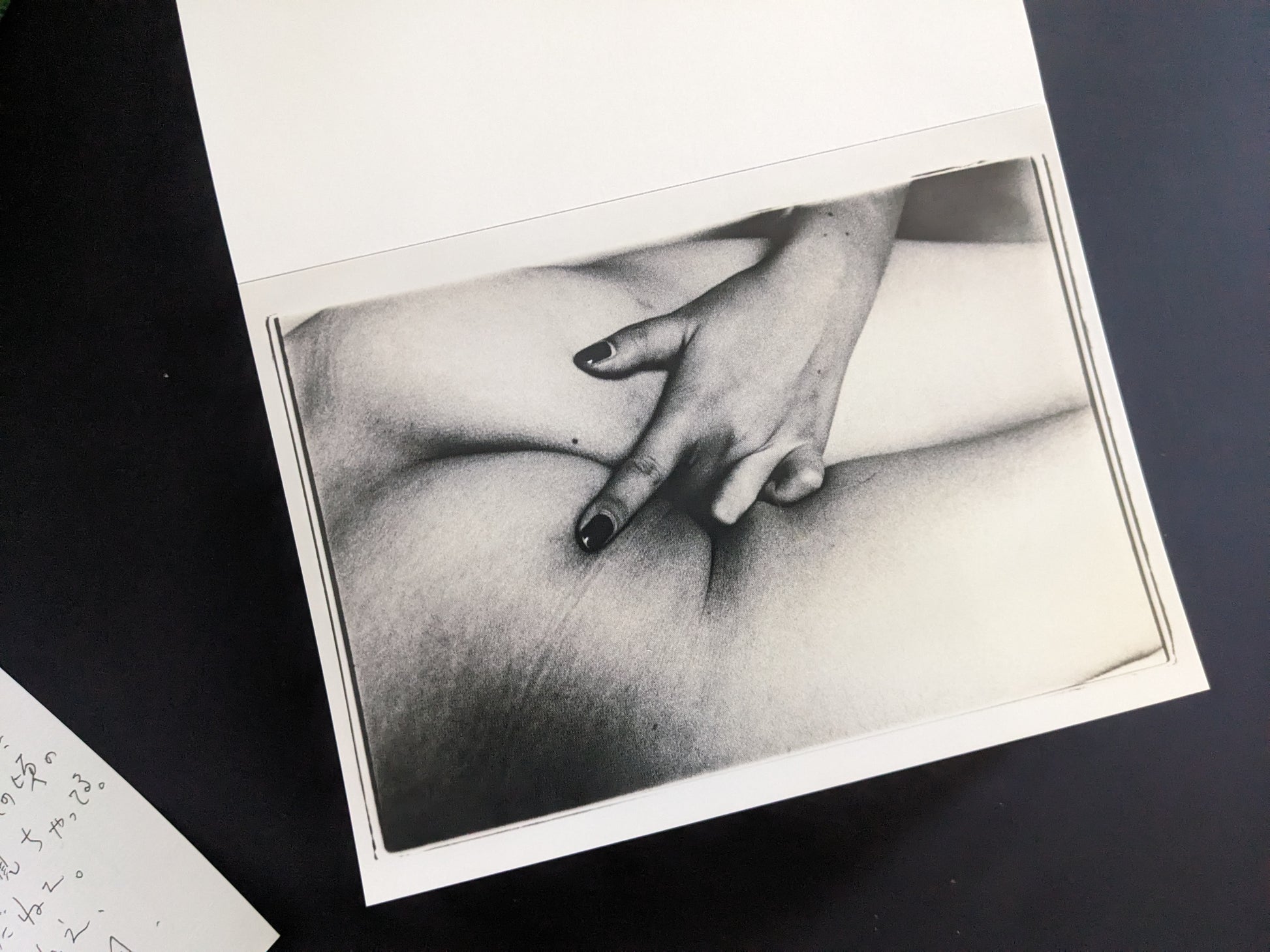 Close-up black-and-white print of a hand on a nude body