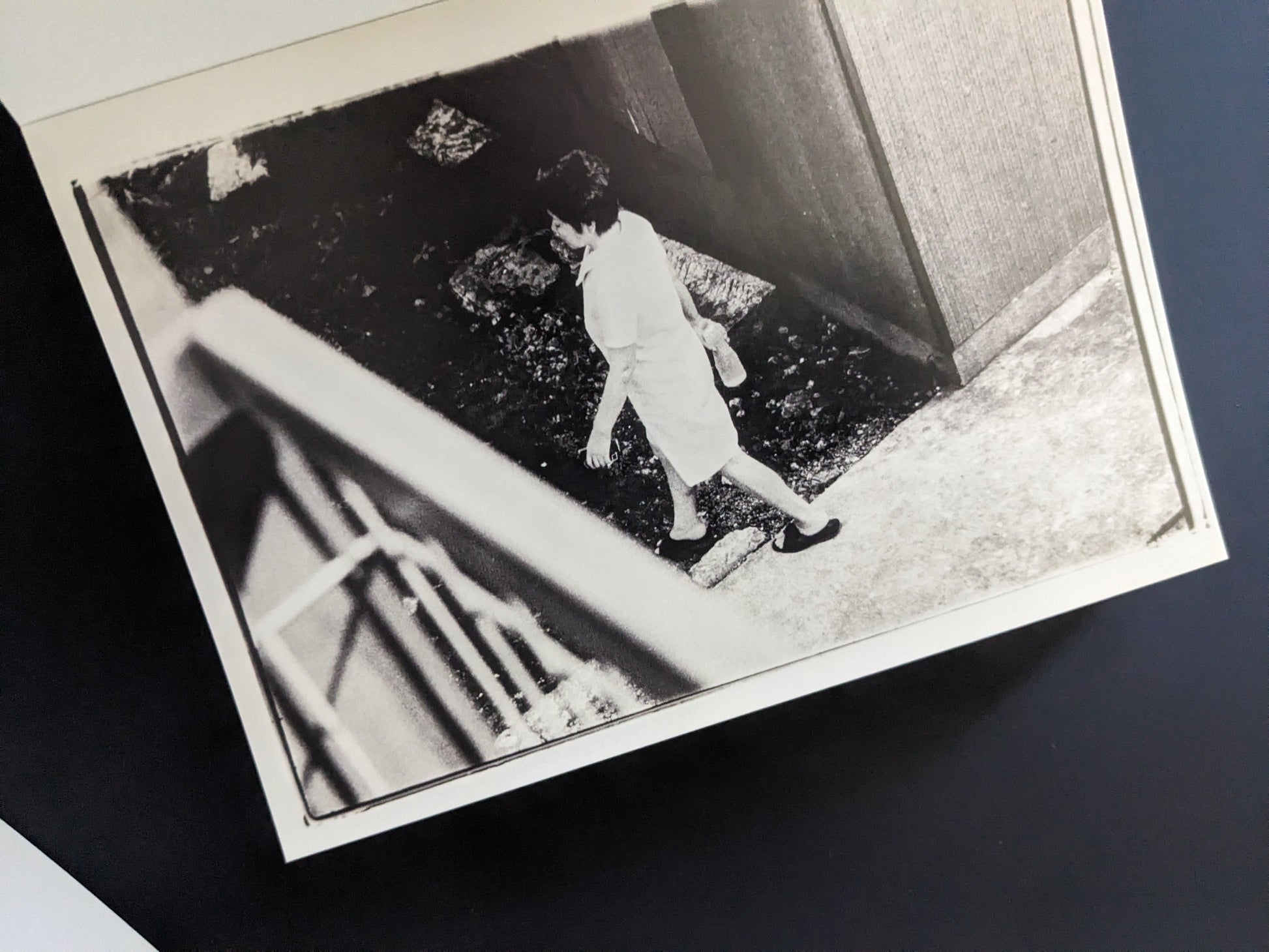 Black-and-white print of a woman in a white dress walking outdoors