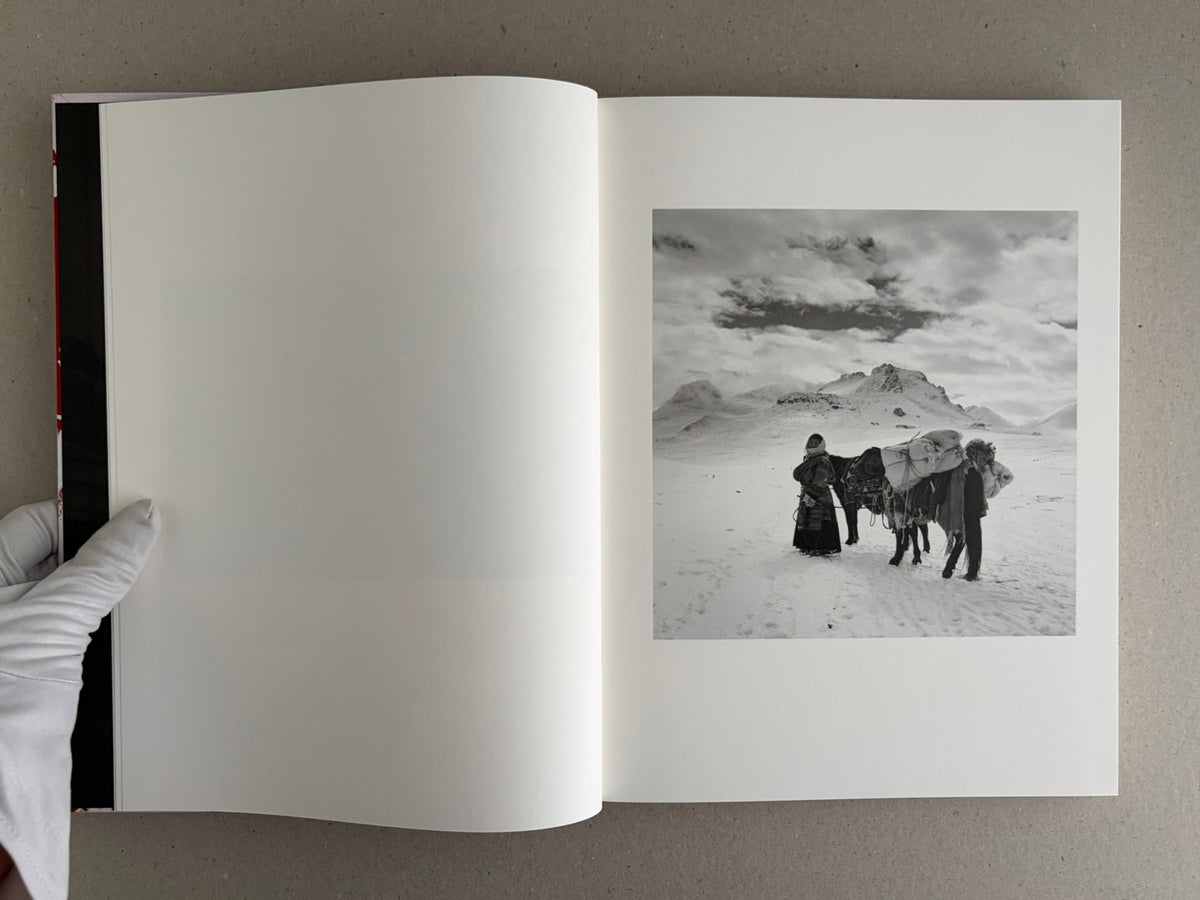Open photobook spread with a black-and-white landscape of a person and a horse on the right page, Tibet – Shinya Arimoto