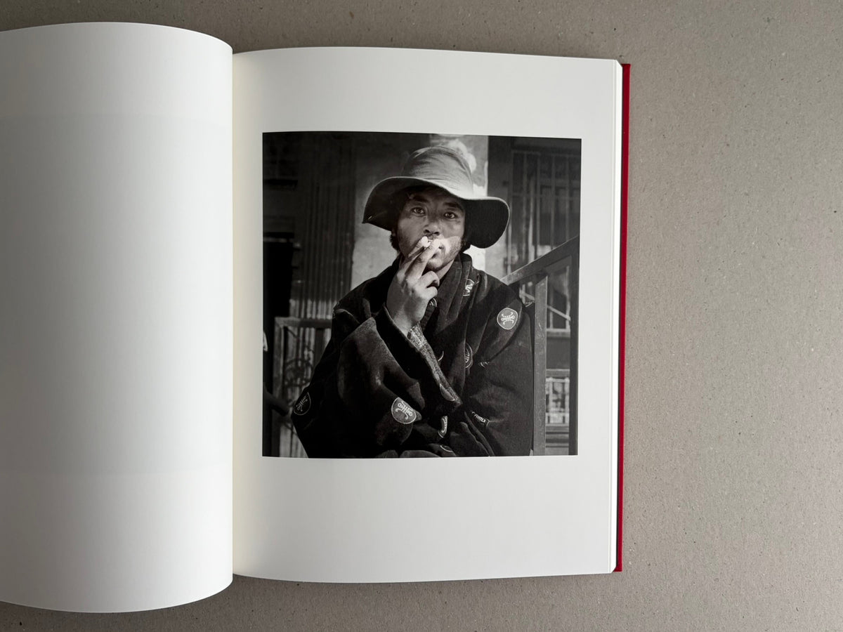 Open photobook spread with a black-and-white portrait on the right page, Tibet – Shinya Arimoto