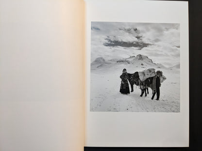Inside page from “TIBET” showing two figures and a loaded pack horse standing on a snowy plateau with mountains in the background.