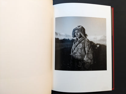 Inside page from “TIBET” with a portrait of a young woman wearing a patterned coat and hood in an outdoor landscape.