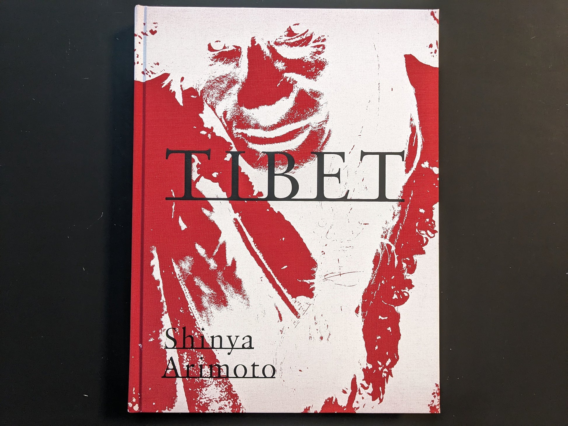 Cover of the photobook “TIBET” by Shinya Arimoto with a high-contrast red and white portrait and the title across the centre.
