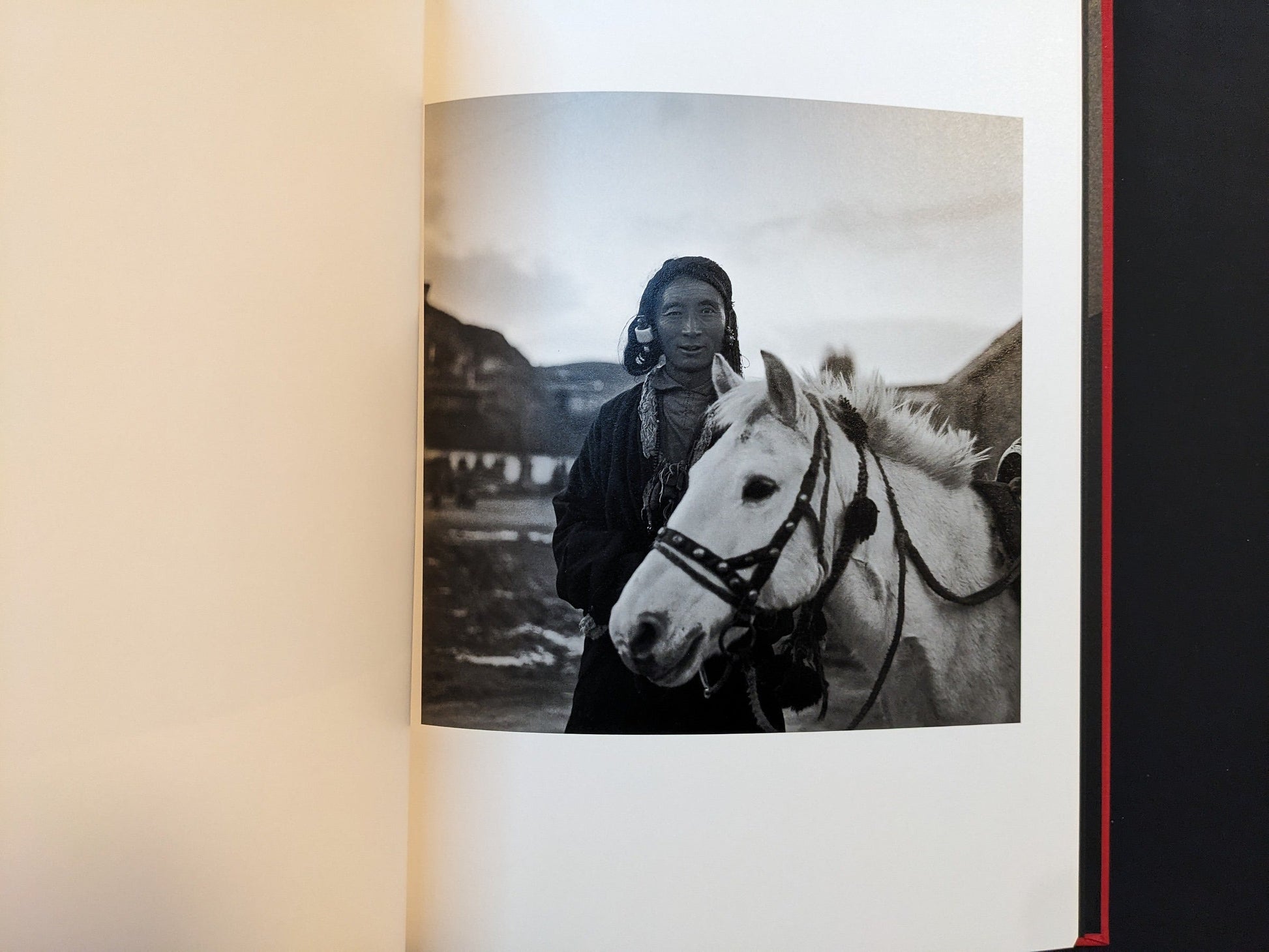 Inside page from Tibet with a rider beside a white horse in a rural landscape.