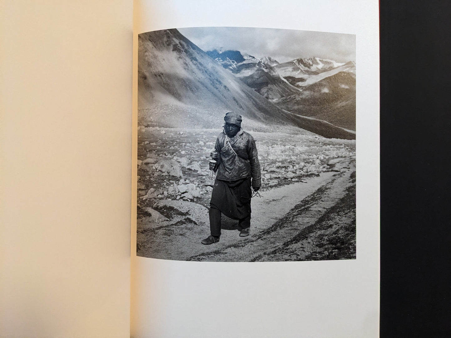 Inside page from Tibet showing a solitary figure walking along a rough mountain path.