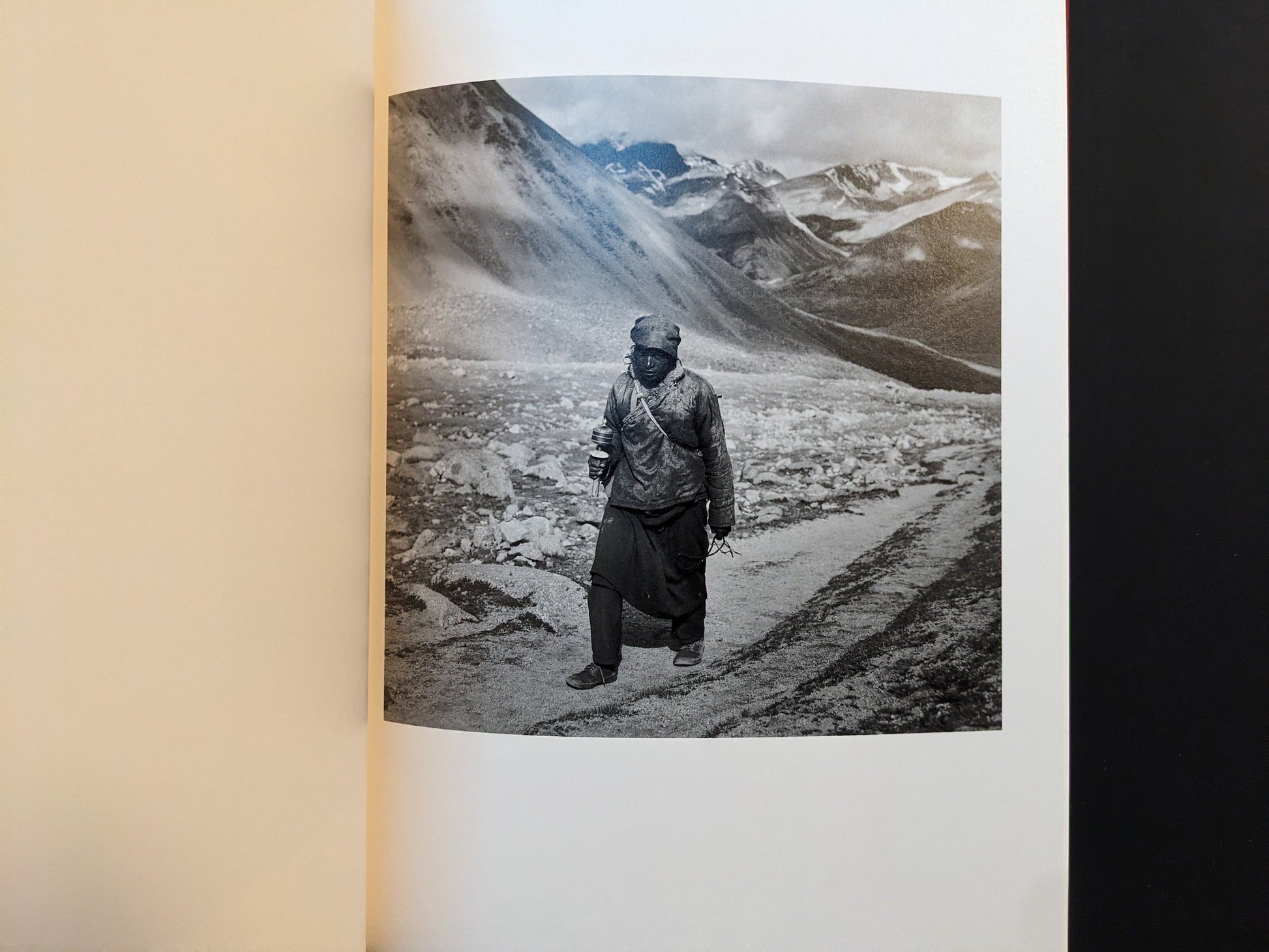 Inside page from Tibet showing a solitary figure walking along a rough mountain path.