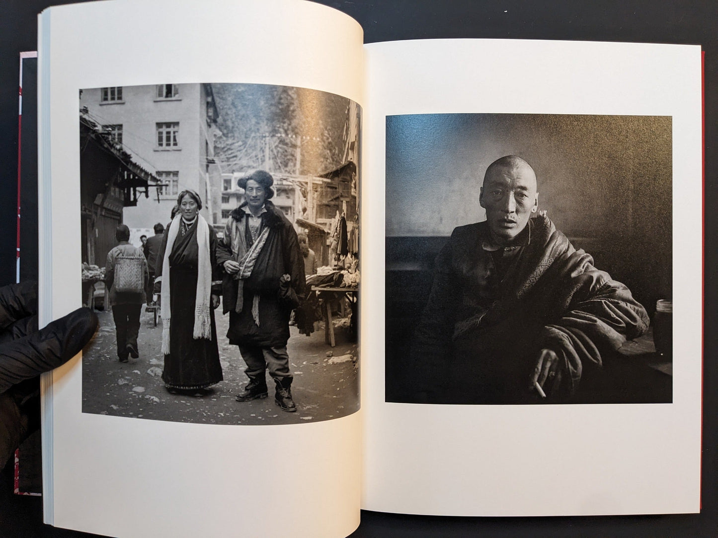 Spread from “TIBET” with a Tibetan couple standing in a busy street scene and a dark interior portrait of a seated monk.