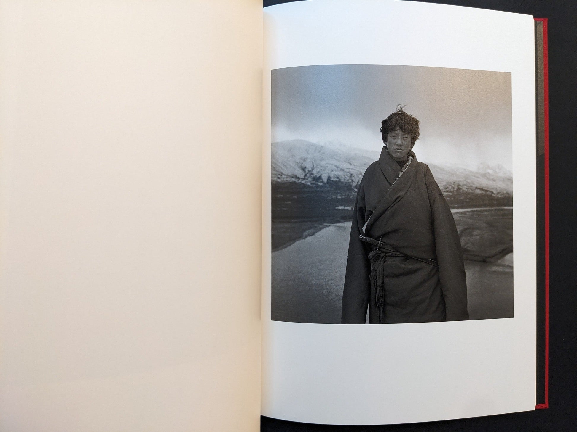 Inside page from Tibet showing a man in traditional clothing before distant snow-covered mountains.