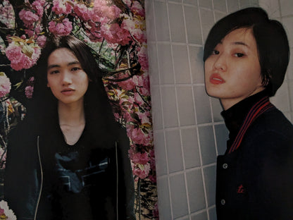 Two women standing in front of a floral curtain and tiled wall.