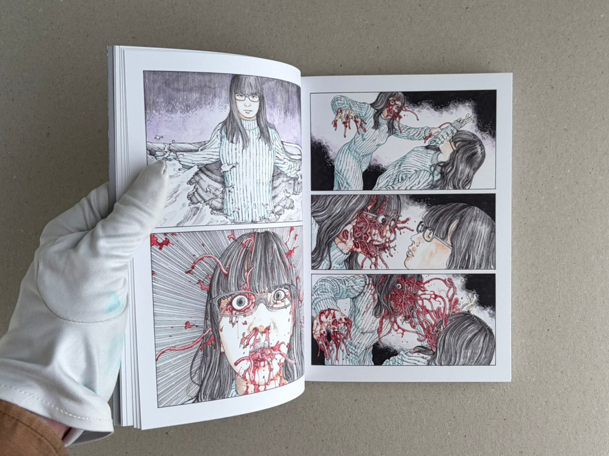 Open TRACT (pocket edition) by Shintaro Kago, showing interior comic pages with a gloved hand holding the book.