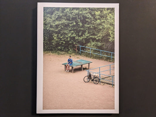 Front cover of TTP by Hayahisa Tomiyasu, featuring a photograph of a boy standing near a ping pong table in a sandy playground.